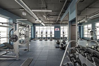 a gym full of equipment and free weights at Reveal Hackensack apartments